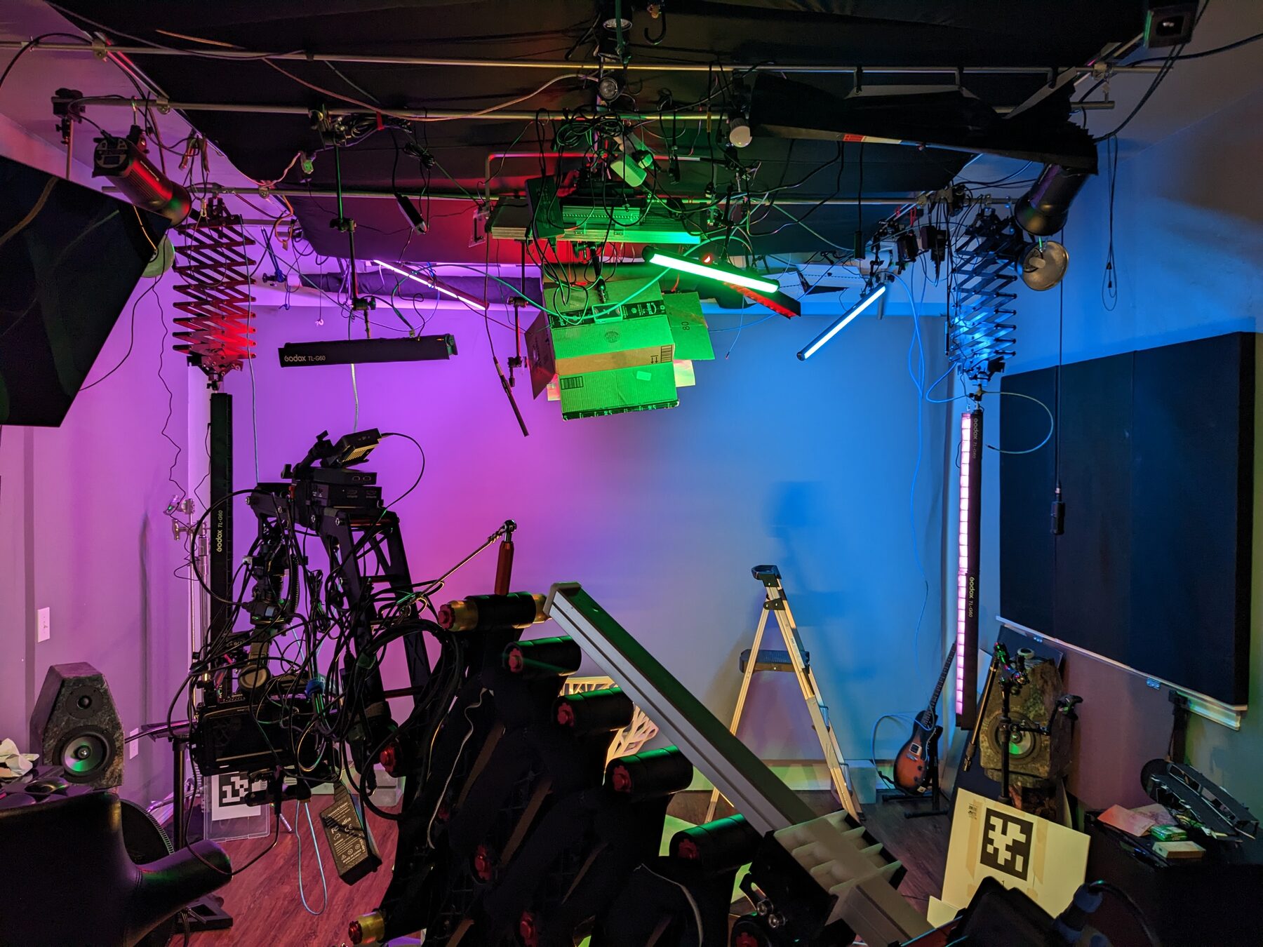 Studio lighting rig with colored tubes, panels, and a camera on a jib